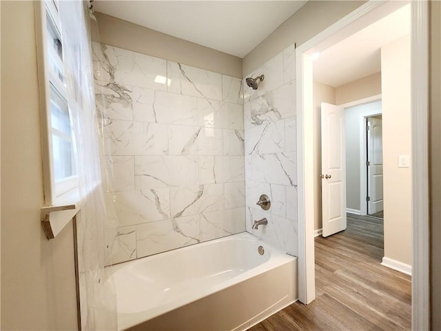 bathroom with hardwood / wood-style flooring and tiled shower / bath