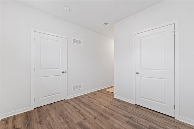 unfurnished bedroom featuring baseboards, visible vents, and wood finished floors