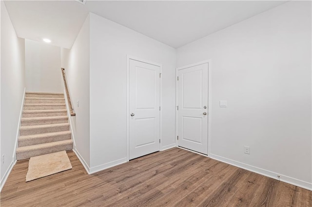 unfurnished room with stairway, wood finished floors, and baseboards