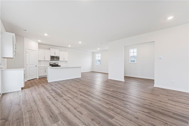 unfurnished living room featuring recessed lighting, light wood-type flooring, visible vents, and baseboards