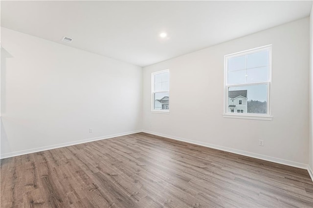 empty room with light wood-style floors, visible vents, baseboards, and a wealth of natural light