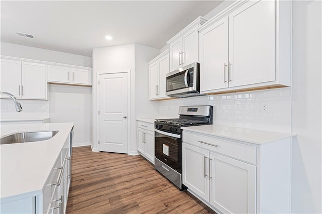 kitchen featuring stainless steel appliances, light countertops, a sink, and white cabinetry