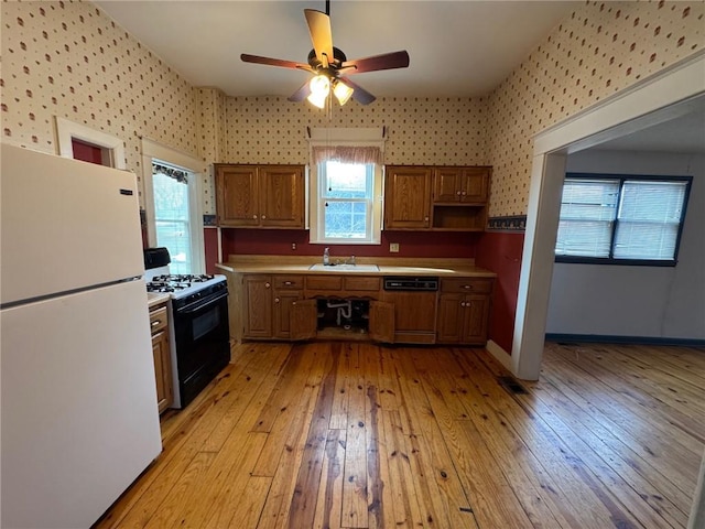 kitchen with sink, gas range, white refrigerator, dishwasher, and light hardwood / wood-style floors