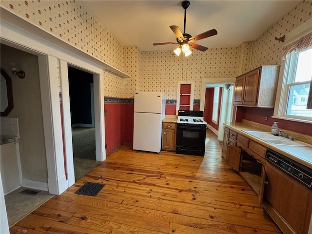 kitchen featuring dishwashing machine, sink, range with gas stovetop, light hardwood / wood-style floors, and white fridge