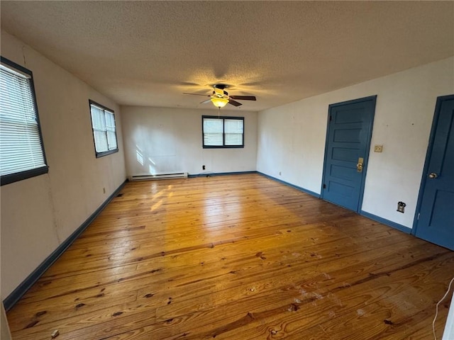 spare room featuring ceiling fan, wood-type flooring, a healthy amount of sunlight, a textured ceiling, and a baseboard radiator