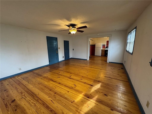 empty room with a textured ceiling, light hardwood / wood-style flooring, and ceiling fan