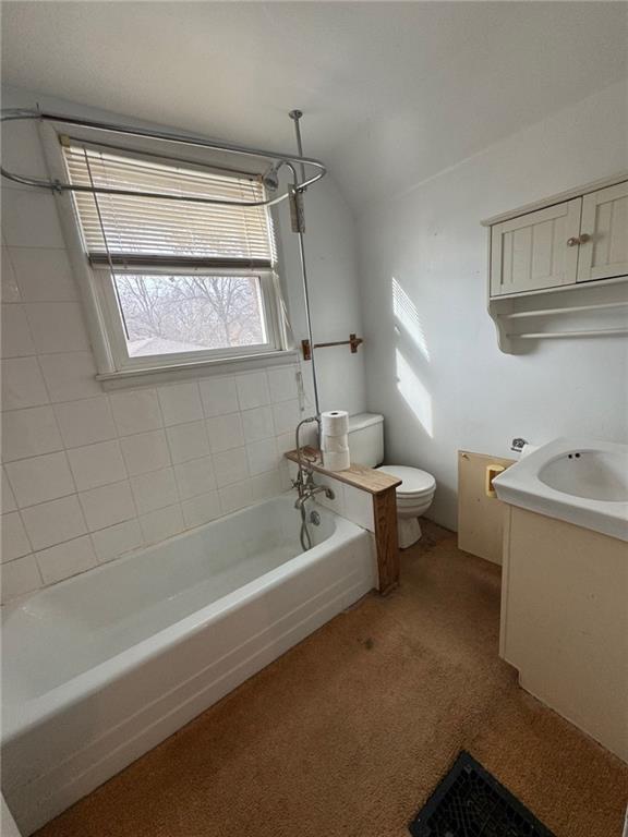 full bathroom featuring tiled shower / bath combo, vanity, lofted ceiling, and toilet