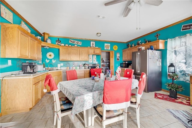 kitchen with sink, crown molding, ceiling fan, light tile patterned floors, and stainless steel refrigerator