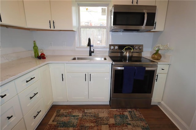 kitchen featuring sink, light stone counters, dark hardwood / wood-style floors, stainless steel appliances, and white cabinets