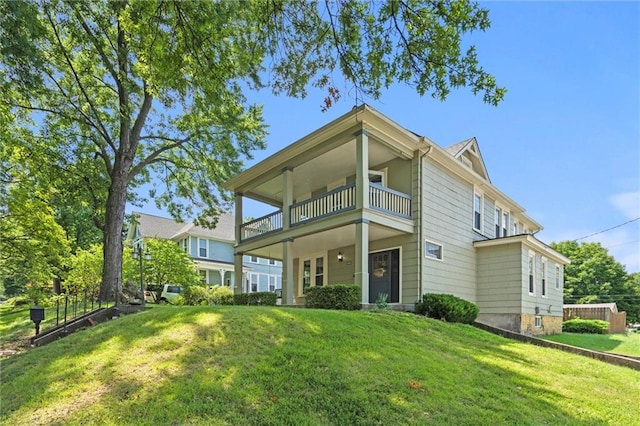 rear view of house with a lawn and a balcony