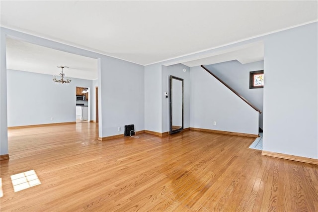 unfurnished living room with a chandelier and light wood-type flooring