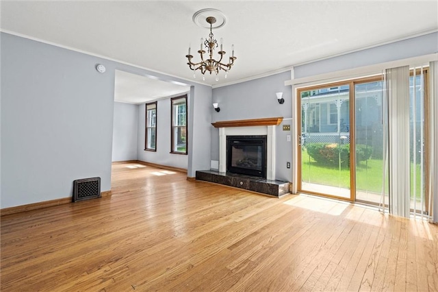 unfurnished living room featuring plenty of natural light, an inviting chandelier, crown molding, and light hardwood / wood-style flooring