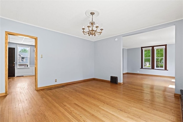 unfurnished room featuring ornamental molding, a notable chandelier, and light wood-type flooring