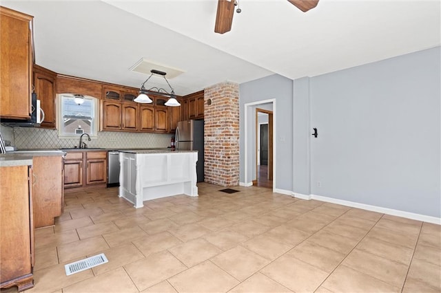 kitchen with a center island, hanging light fixtures, ceiling fan, appliances with stainless steel finishes, and tasteful backsplash