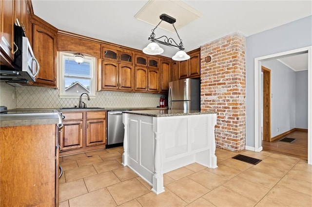 kitchen with sink, stainless steel appliances, tasteful backsplash, pendant lighting, and a kitchen island