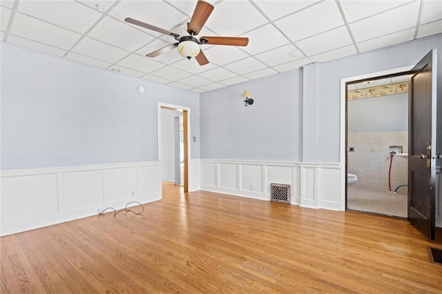 empty room featuring a paneled ceiling, ceiling fan, and light wood-type flooring