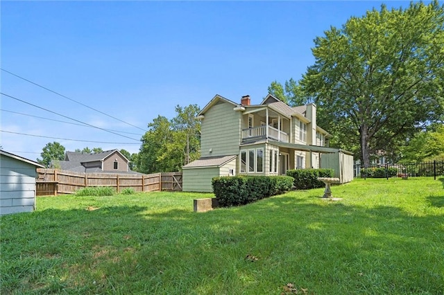 rear view of property featuring a balcony and a yard