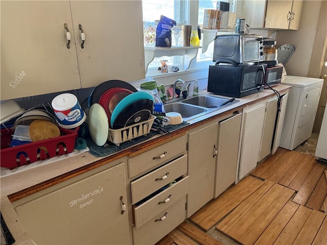 kitchen featuring white cabinets, washer / dryer, light hardwood / wood-style floors, and sink