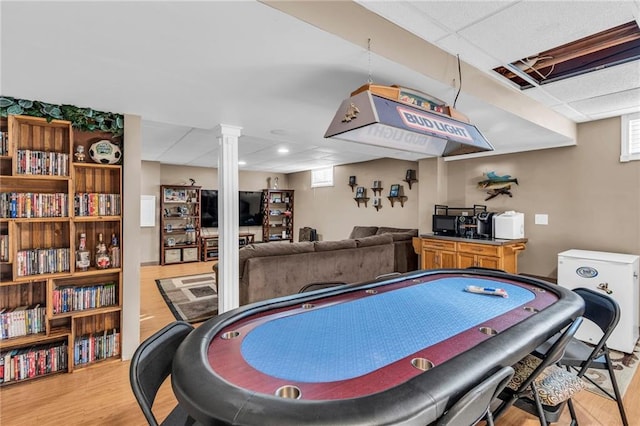 playroom featuring light hardwood / wood-style floors, ornate columns, and a drop ceiling