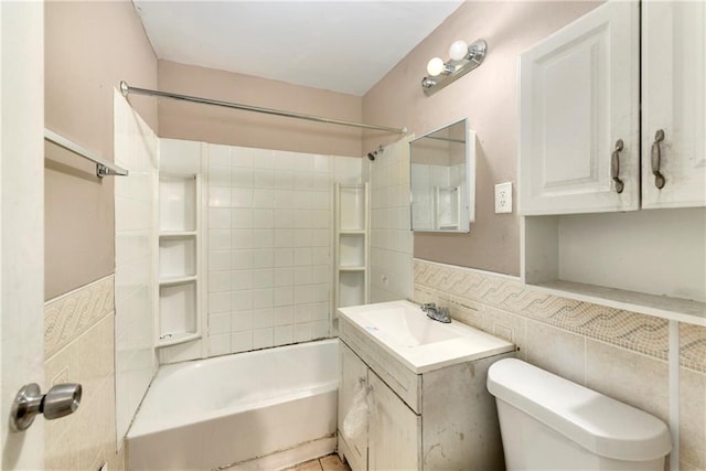 full bathroom featuring tile walls, toilet, tile patterned floors, vanity, and tiled shower / bath combo