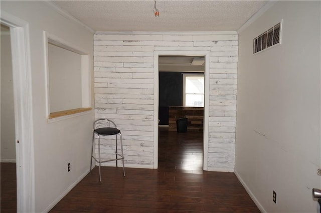 hallway with crown molding, dark hardwood / wood-style flooring, and a textured ceiling