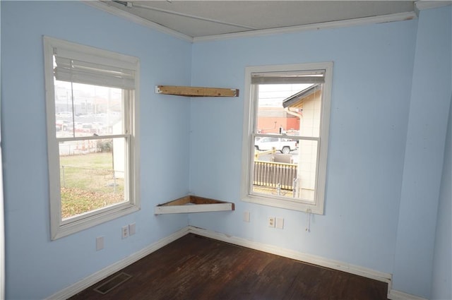 empty room featuring a wealth of natural light, dark hardwood / wood-style floors, and ornamental molding