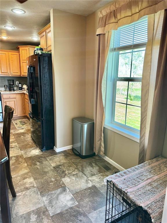 kitchen with black refrigerator, light brown cabinets, and plenty of natural light