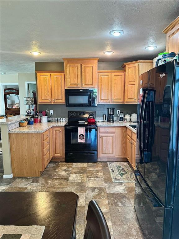 kitchen featuring black appliances, light stone counters, and a textured ceiling