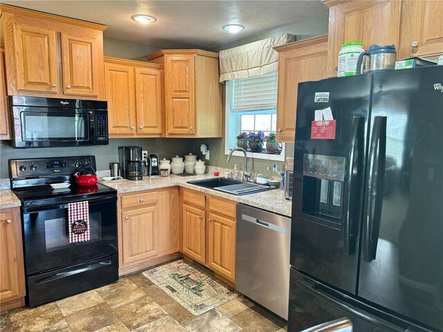 kitchen featuring light stone countertops, sink, and black appliances