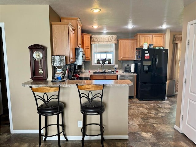 kitchen with a breakfast bar, black fridge, sink, stainless steel dishwasher, and kitchen peninsula