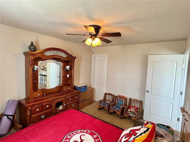 carpeted bedroom with ceiling fan and a textured ceiling