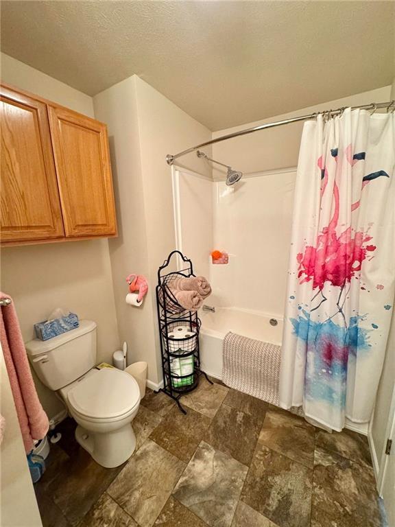 bathroom with shower / bath combination with curtain and toilet