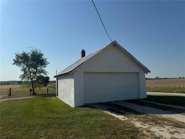 garage with a rural view and a yard