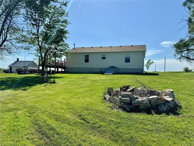 back of house featuring a yard, a deck, and an outdoor fire pit