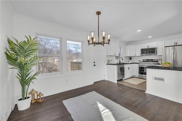 kitchen featuring stainless steel appliances, dark wood-type flooring, white cabinets, a chandelier, and hanging light fixtures