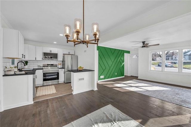 kitchen featuring hanging light fixtures, stainless steel appliances, dark hardwood / wood-style flooring, white cabinets, and ceiling fan with notable chandelier