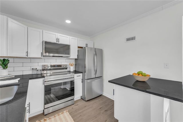 kitchen featuring ornamental molding, appliances with stainless steel finishes, tasteful backsplash, light hardwood / wood-style floors, and white cabinetry