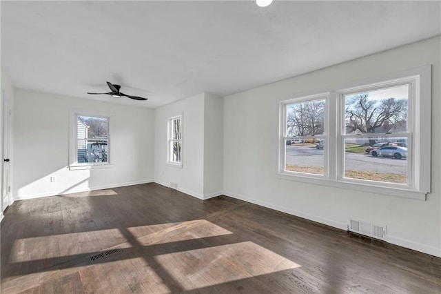 spare room with ceiling fan, plenty of natural light, and dark wood-type flooring