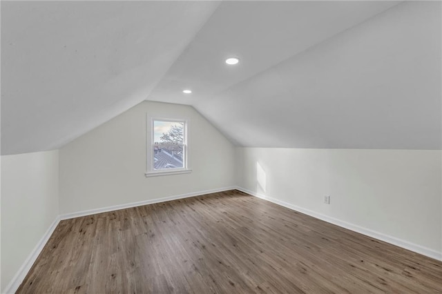 additional living space with hardwood / wood-style flooring and vaulted ceiling