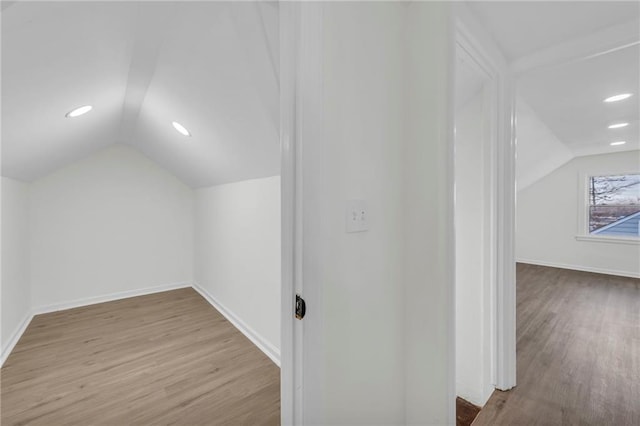 additional living space with light hardwood / wood-style floors and lofted ceiling