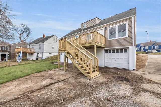 exterior space featuring a deck, a front yard, and a garage