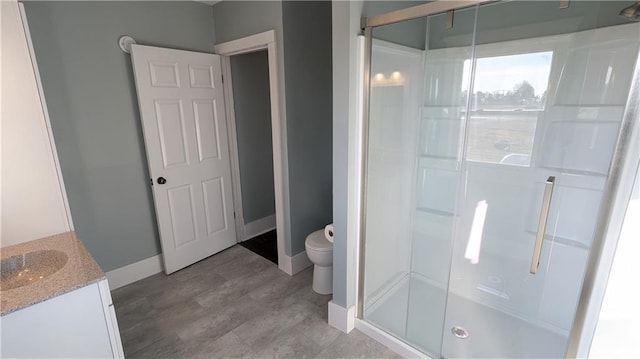 bathroom featuring hardwood / wood-style flooring, vanity, toilet, and a shower with shower door