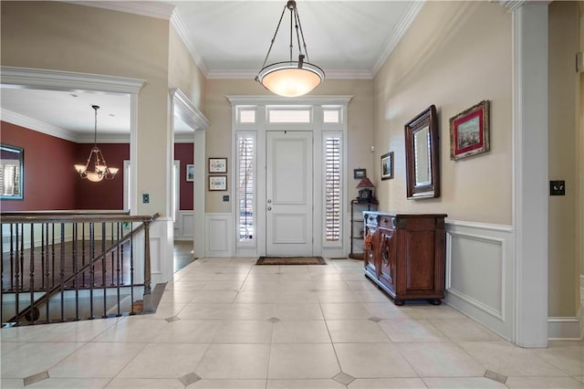 tiled foyer entrance featuring a notable chandelier and crown molding