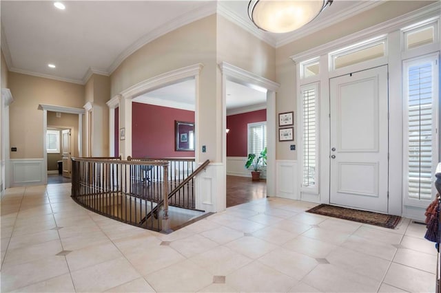 foyer entrance with light tile patterned floors, crown molding, and a wealth of natural light