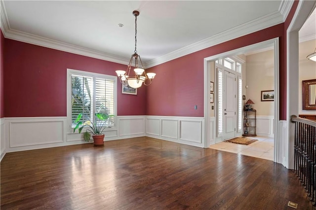 empty room featuring ornamental molding, a chandelier, and hardwood / wood-style floors