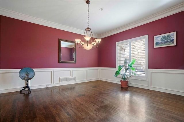 spare room with an inviting chandelier, dark hardwood / wood-style flooring, and crown molding