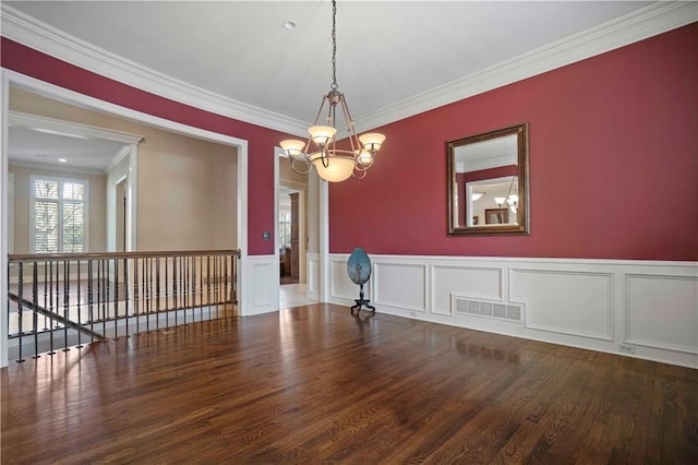 unfurnished room featuring hardwood / wood-style flooring, ornamental molding, and a chandelier