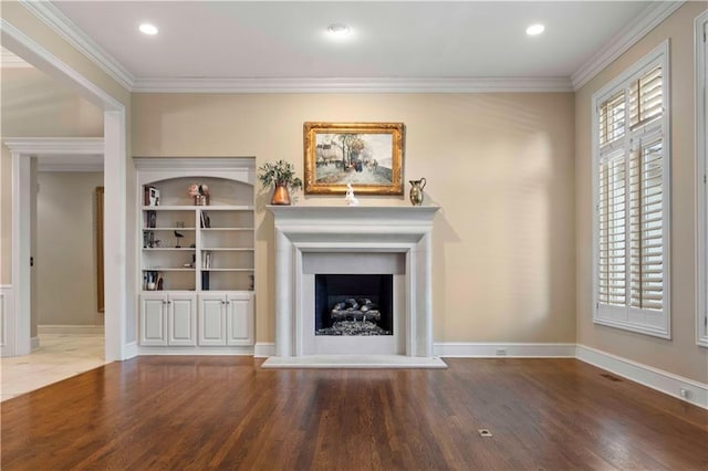 unfurnished living room featuring hardwood / wood-style flooring, ornamental molding, and built in shelves