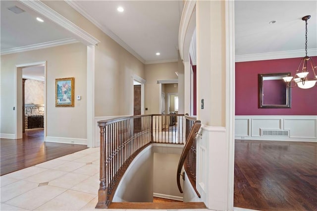 hallway featuring crown molding, light tile patterned floors, and a notable chandelier