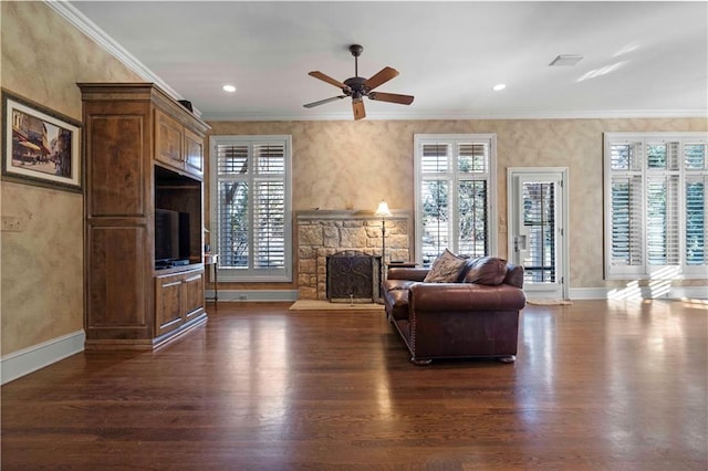 living room featuring ceiling fan, ornamental molding, a stone fireplace, and dark hardwood / wood-style flooring